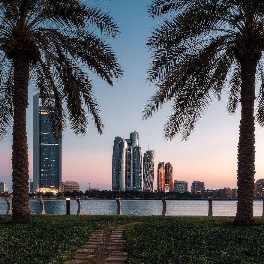 The Abu Dhabi skyline at dusk — Etihad Towers and the Corniche seen through palm trees