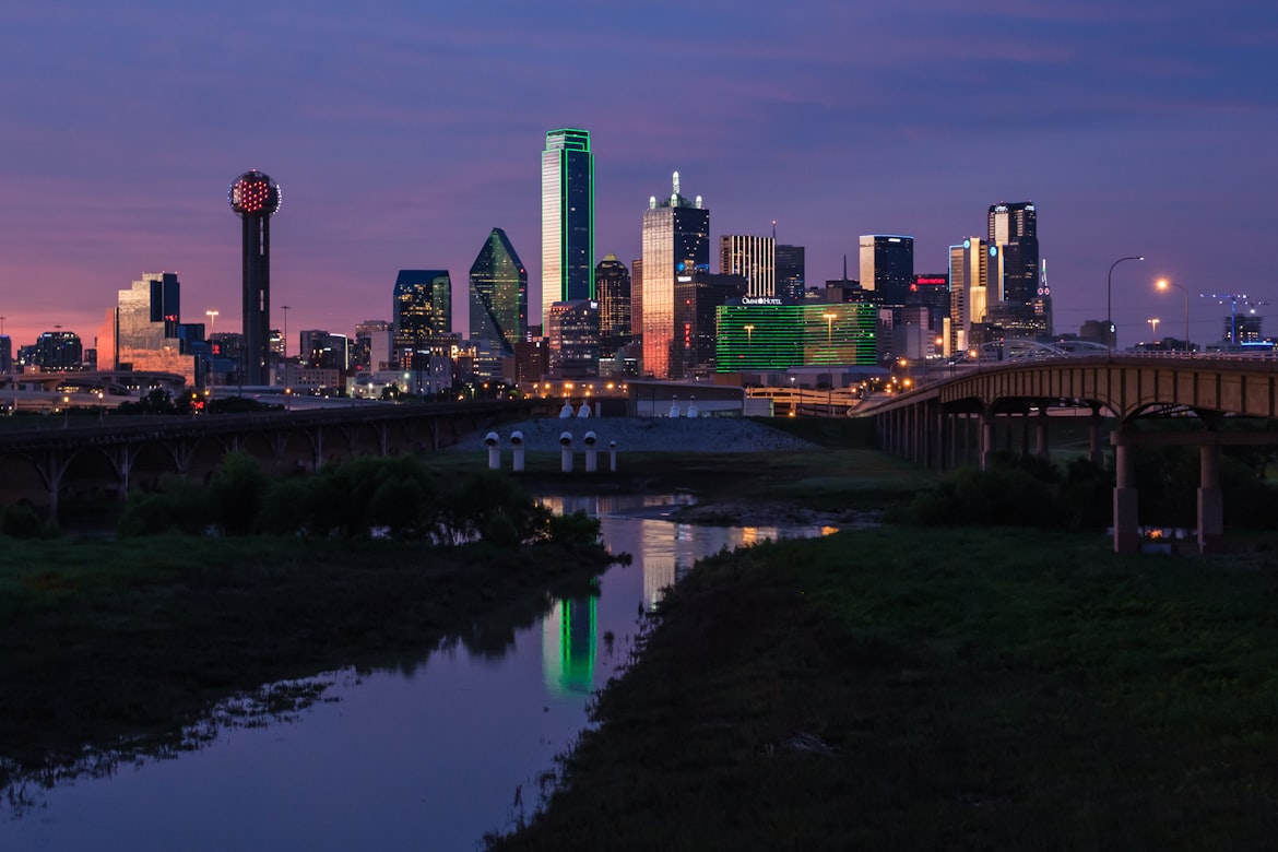 The Dallas skyline at dusk, with Reunion Tower and the downtown towers reflected in the Trinity River