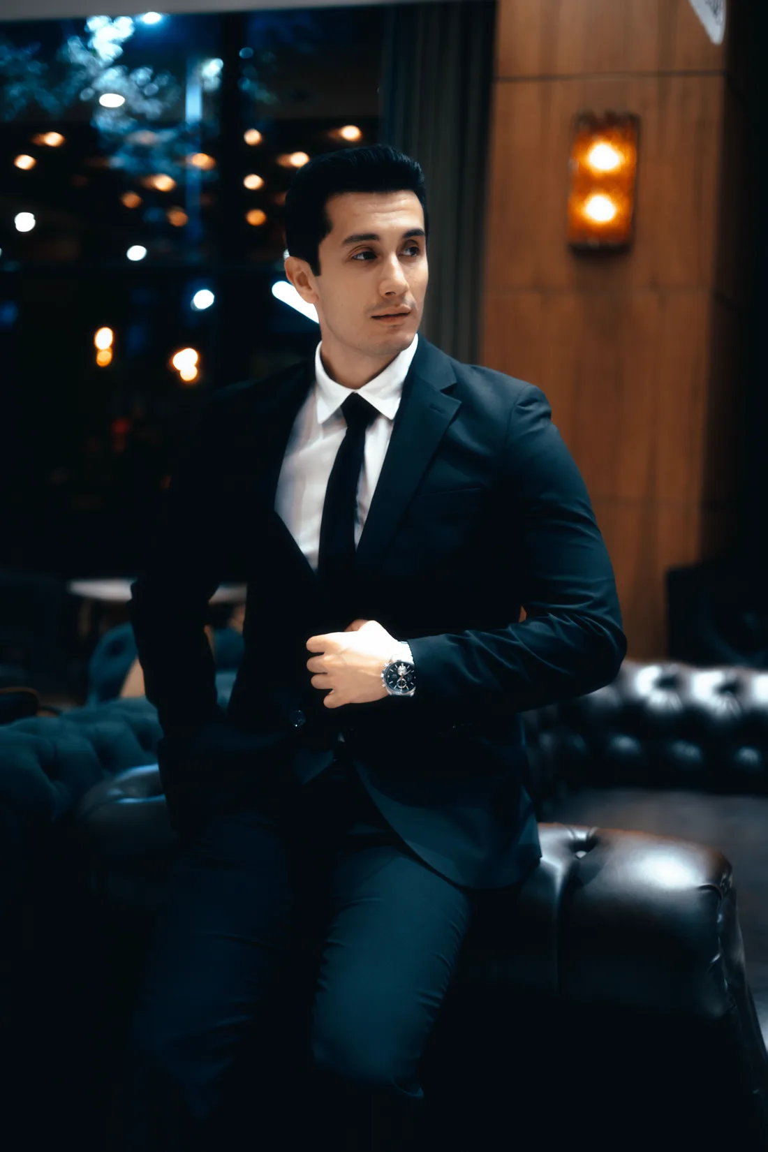 A collector in a dark suit adjusting his cuff, a steel chronograph on his wrist — the considered buyer in the 2026 market
