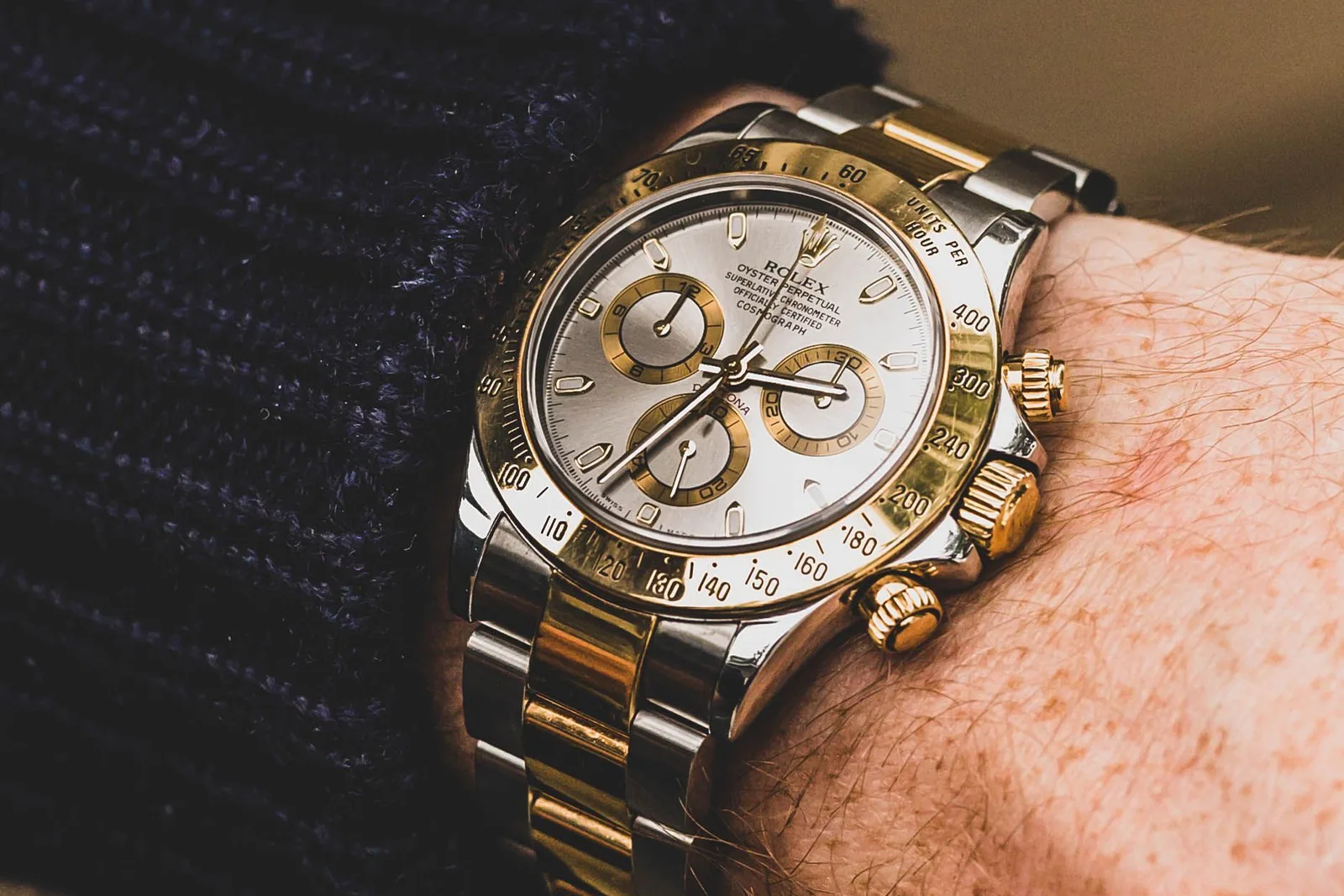 A two-tone steel-and-gold Rolex Cosmograph Daytona with a silver dial, worn on the wrist