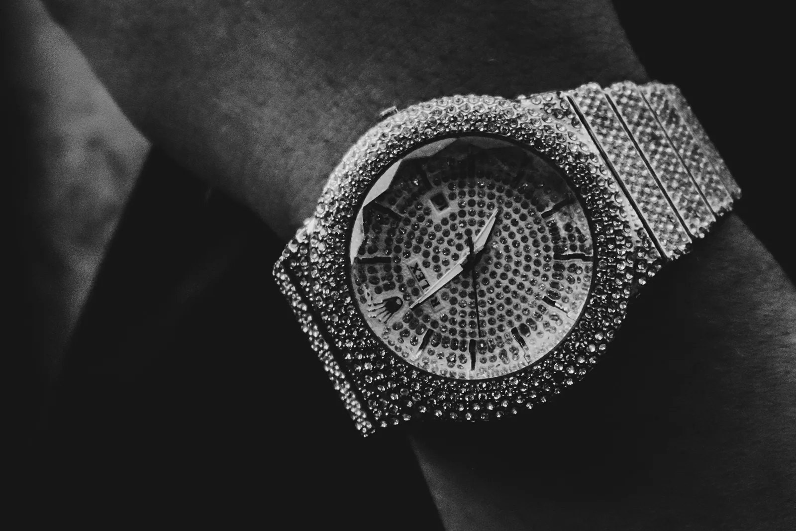 A fully diamond-set watch on a wrist, shot in dramatic black and white — the flex in its purest form